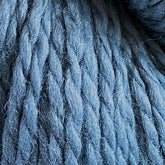 Close-up view of thick, textured blue yarn strands intertwined, showcasing a mix of light and dark fibers for a soft and cozy appearance. Made from Cascade Eco and Cascade Eco Plus Wool Yarn by Cascade Yarns, it offers an environmentally friendly option for your knitting projects.